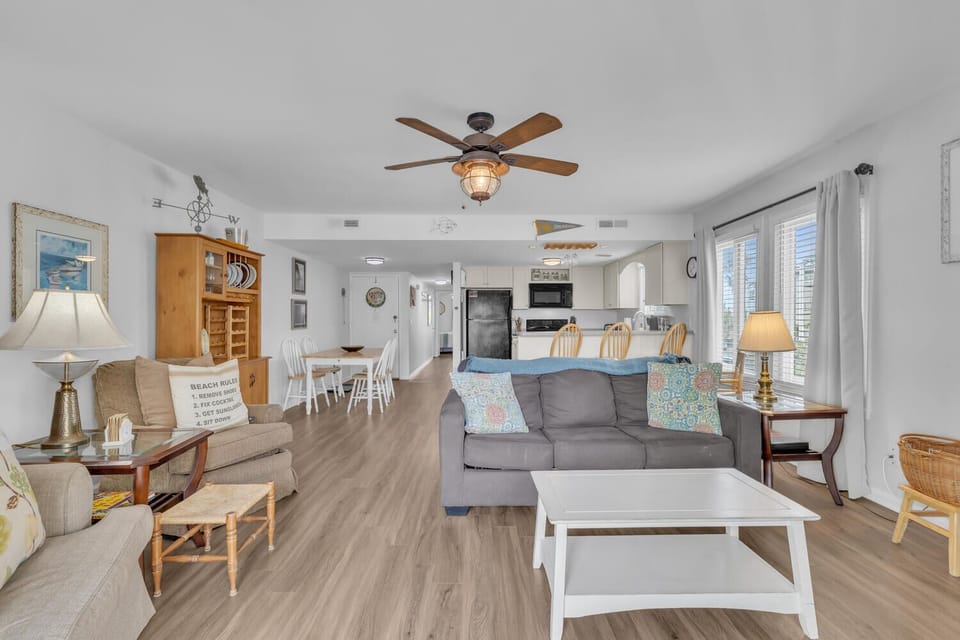 Relax in your spacious open-plan living area with comfortable seating, ceiling fan, and modern kitchen perfectly designed for your beach getaway.