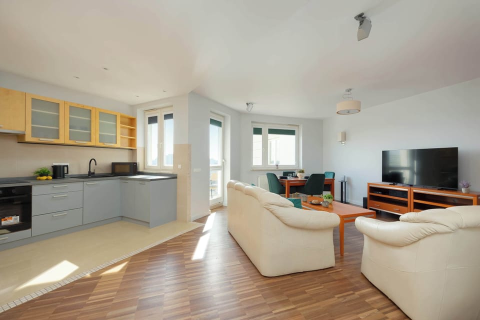 A view of the entire living area, including the kitchenette, the dining table, and the relaxation zone with large windows visible.