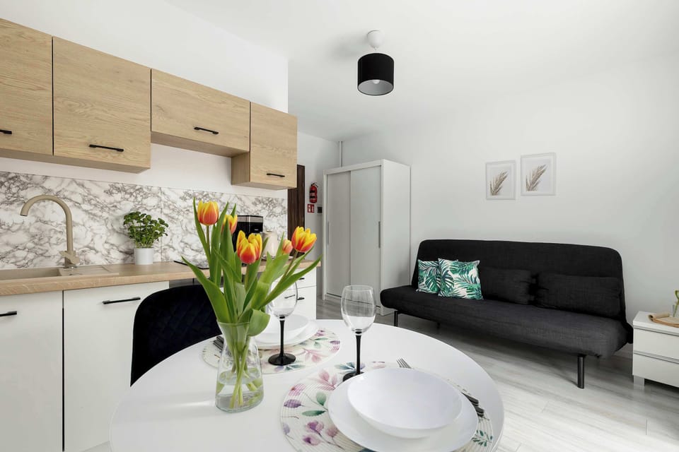 A slightly different perspective of the kitchenette and living area, with a vase of flowers adding a fresh accent. The space feels bright and welcoming.
