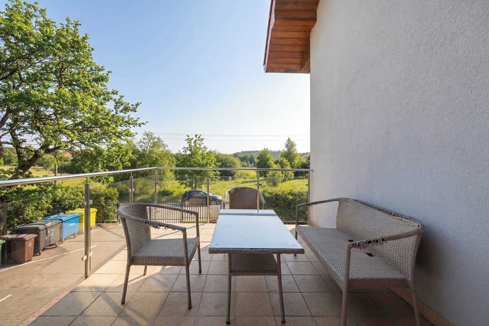 A terrace or balcony view overlooking a green landscape. Outdoor seating allows for enjoying fresh air and scenic surroundings.
