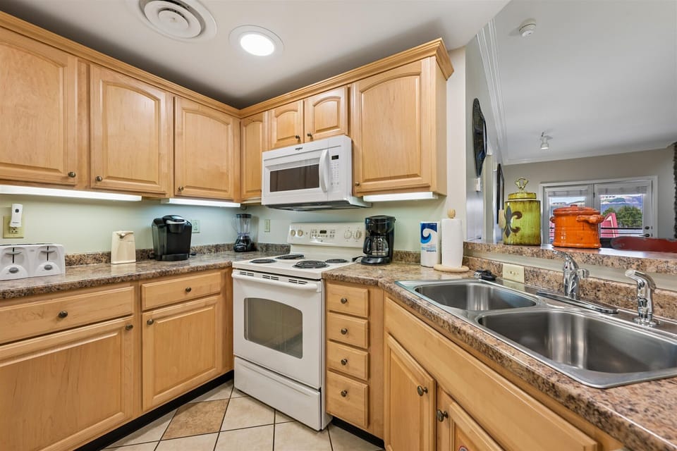 Your fully equipped kitchen awaits with warm wood cabinets, granite counters, and everything needed to create memorable meals during your stay.