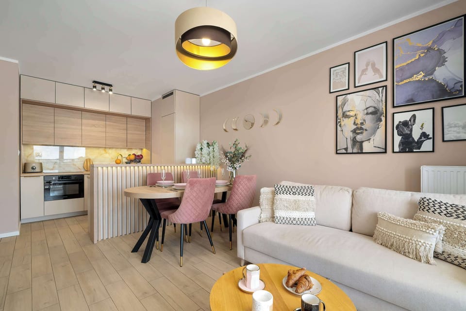 A stylishly decorated living room includes a comfortable cream-colored sofa positioned near a dining table illuminated by warm lighting.