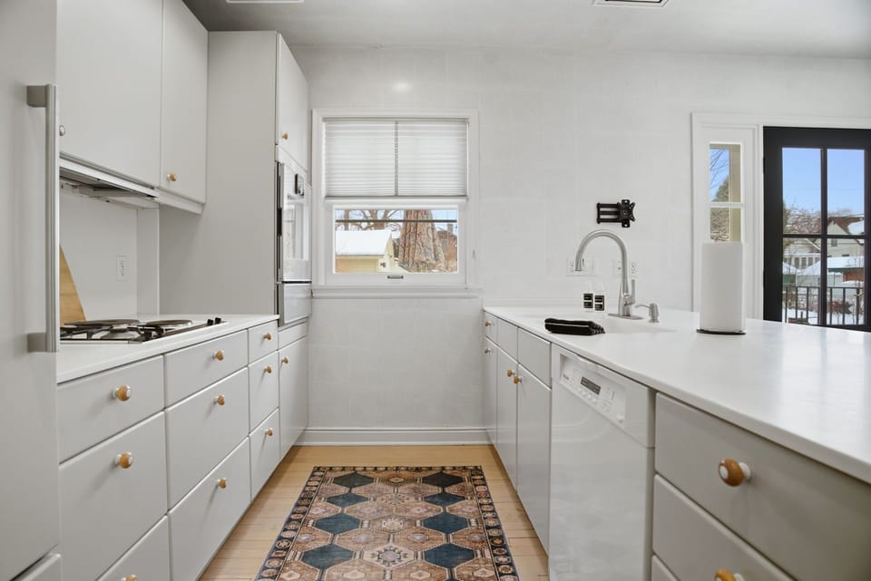 Your bright, modern kitchen awaits with sleek white cabinetry, stainless steel appliances, and warm wood accents that create the perfect space for cooking.