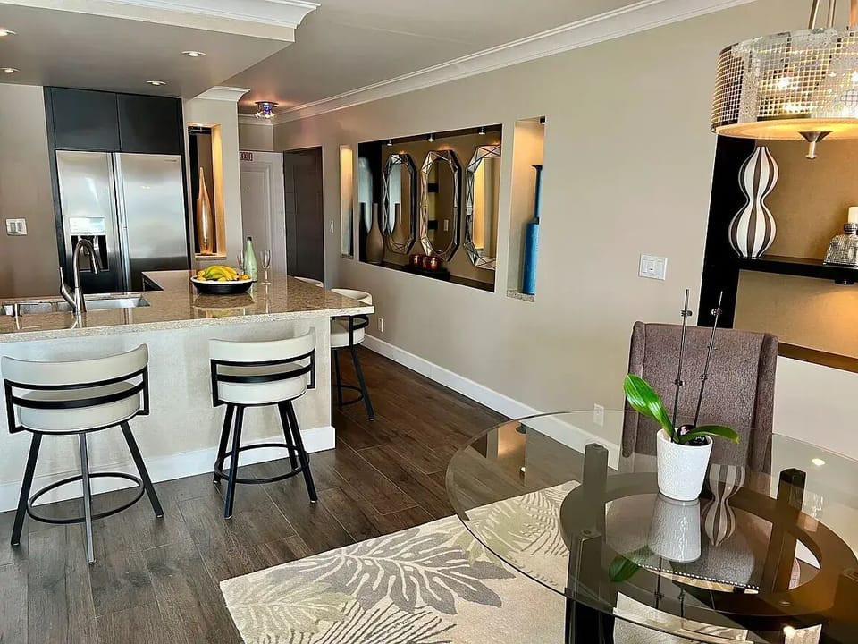Dining table in foreground. Background is granite island with luxury chairs.