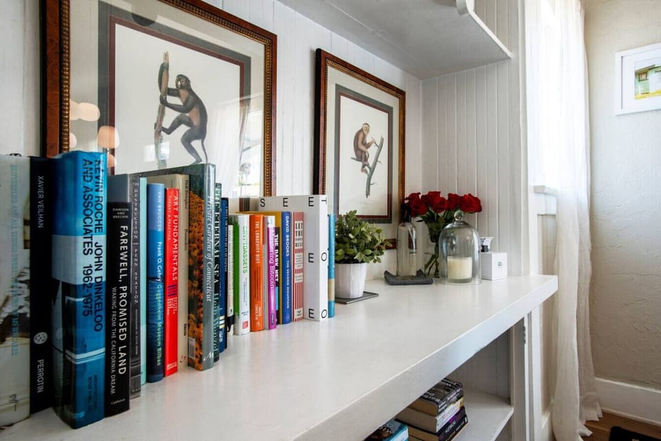 Curl up with a good book from our curated library shelf — stocked with an eclectic mix of titles and framed by fresh flowers and artwork for a warm, homey touch.