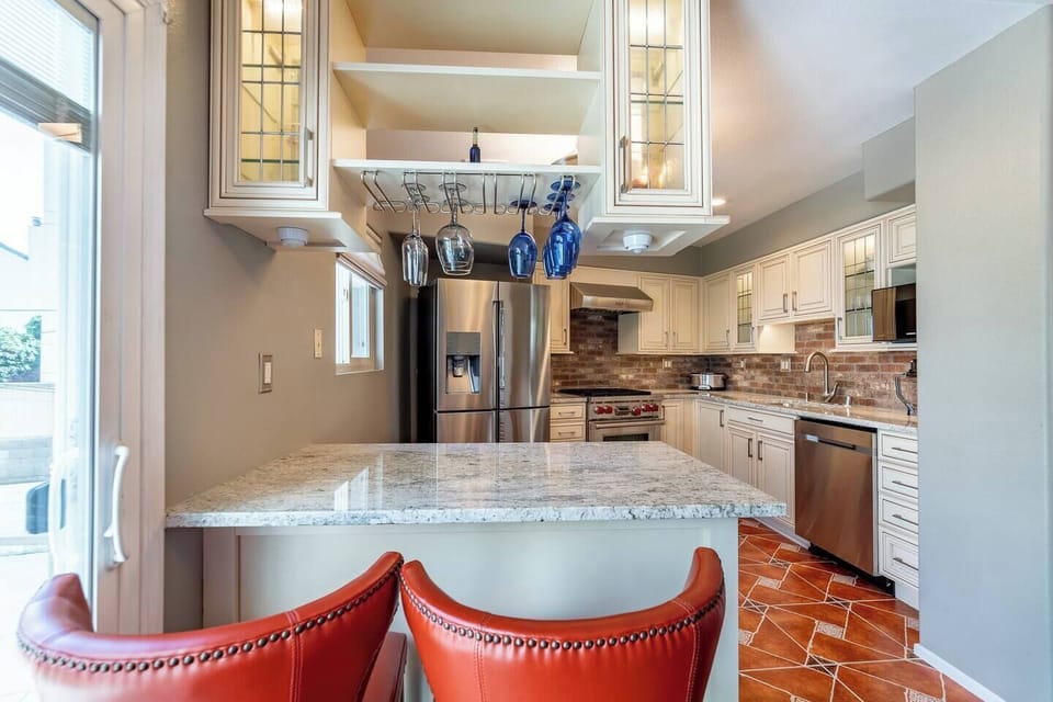 Cook and gather in this gorgeous chef`s kitchen featuring a large granite island, stainless steel appliances, brick backsplash, and plenty of cabinet space for everything you need.