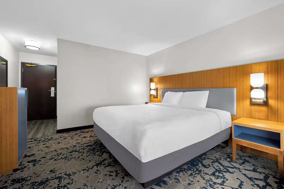 Unwind in a crisp king bed with warm lighting.