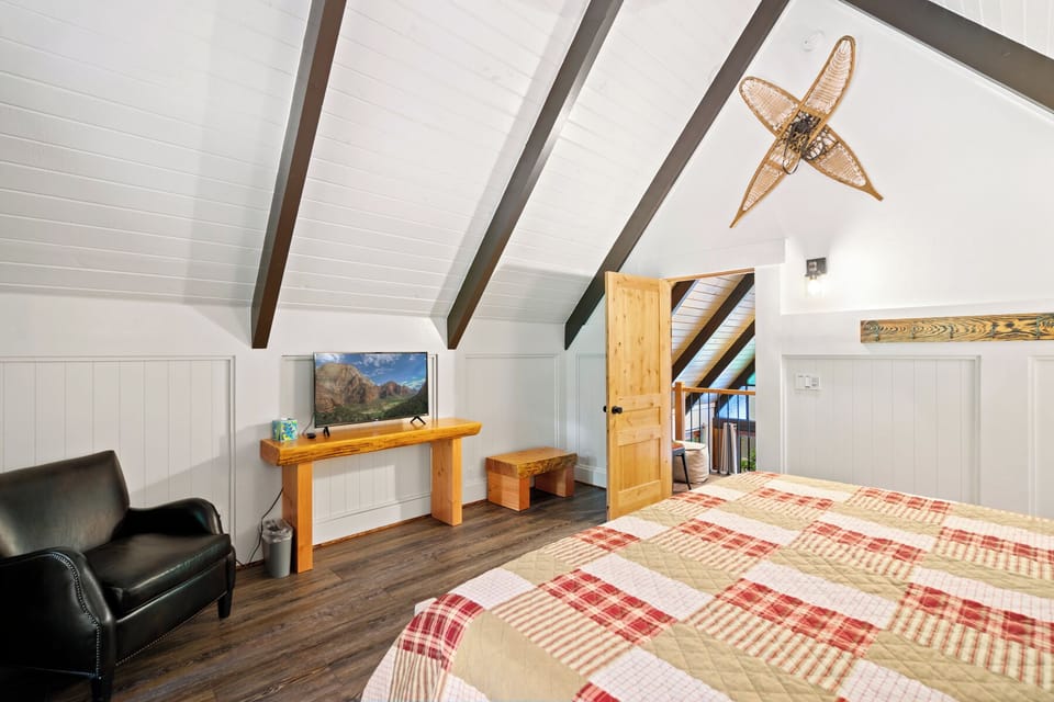 Spacious loft with exposed beam ceiling, smart TV, work desk, and cozy reading chair