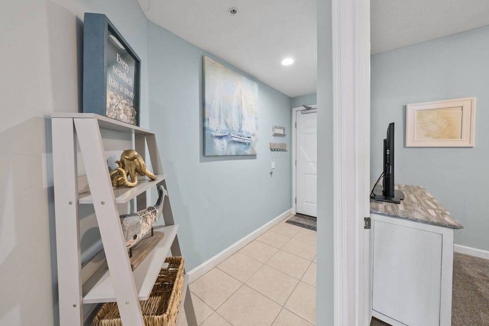 Welcoming entryway with coastal-themed shelving, sailboat artwork, and charming beach décor setting the tone for your stay.