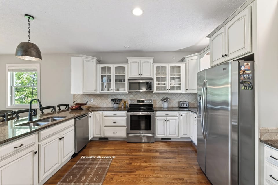 Spacious chef’s kitchen with granite island, bar seating, and stainless steel appliances—perfect for gathering and entertaining.