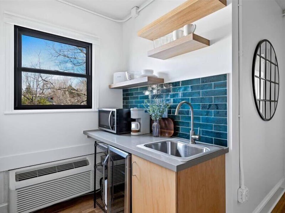Enjoy the convenience of a well-equipped kitchenette featuring a mini fridge, microwave, sink, coffee maker, and open shelving — ideal for preparing light meals and morning coffee during your stay. Layout and shelving may vary slightly by unit.