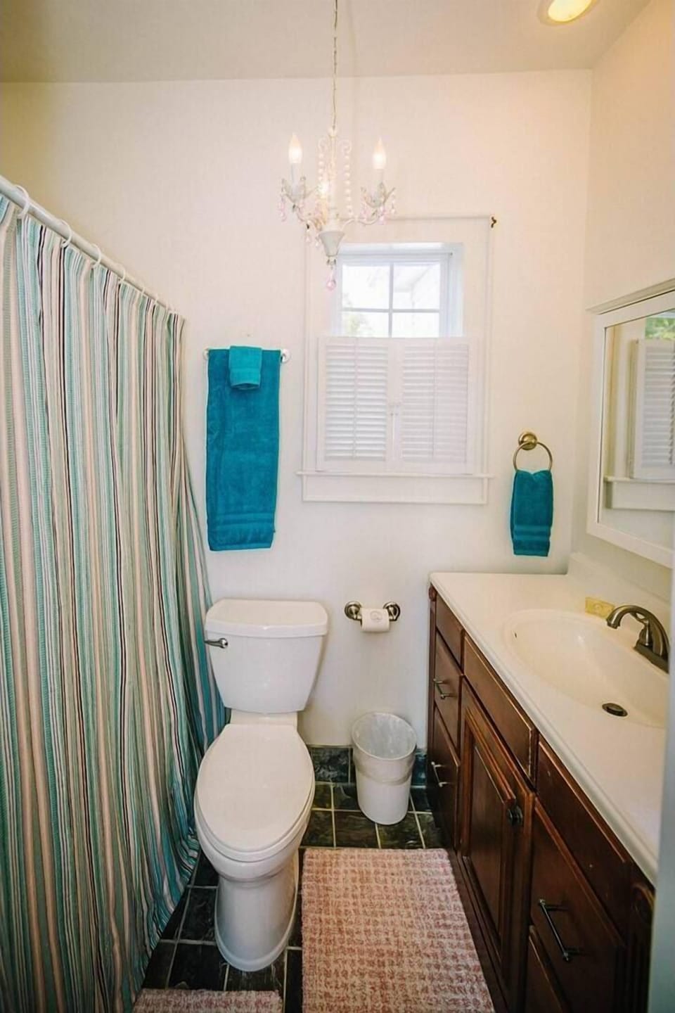 The full bathroom features a spacious vanity with plenty of storage, a clean shower-tub combination, and charming vintage lighting for a bright and refreshing space.