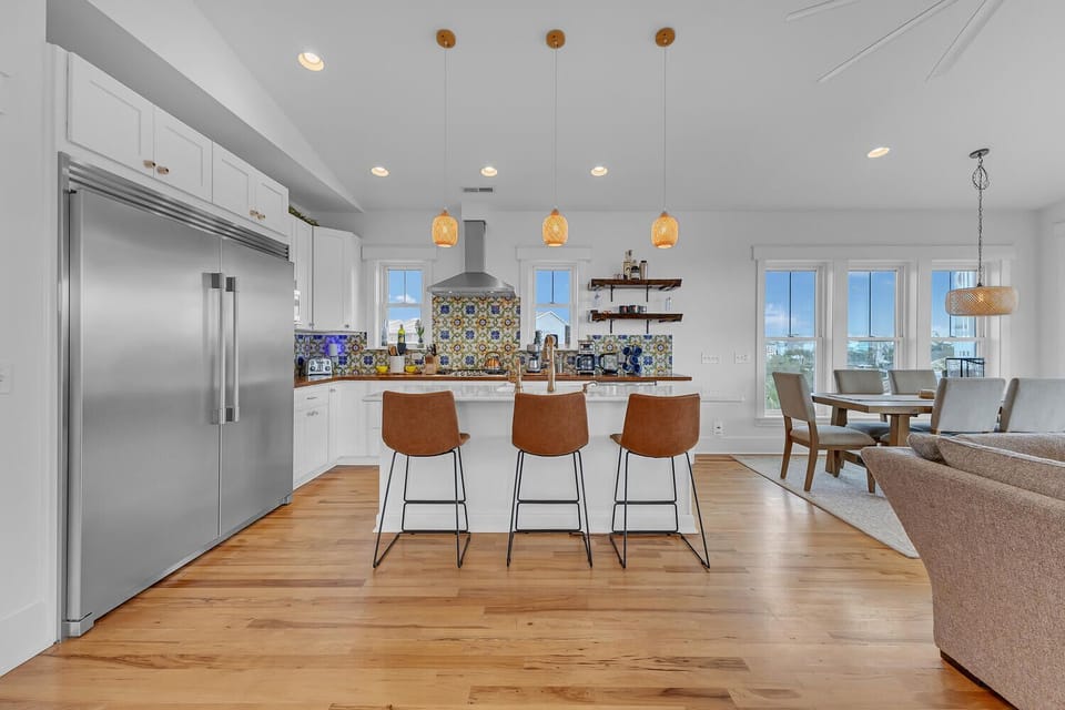 You'll love cooking in this bright, modern kitchen with its stunning backsplash, spacious island, and warm pendant lighting creating the perfect gathering spot.