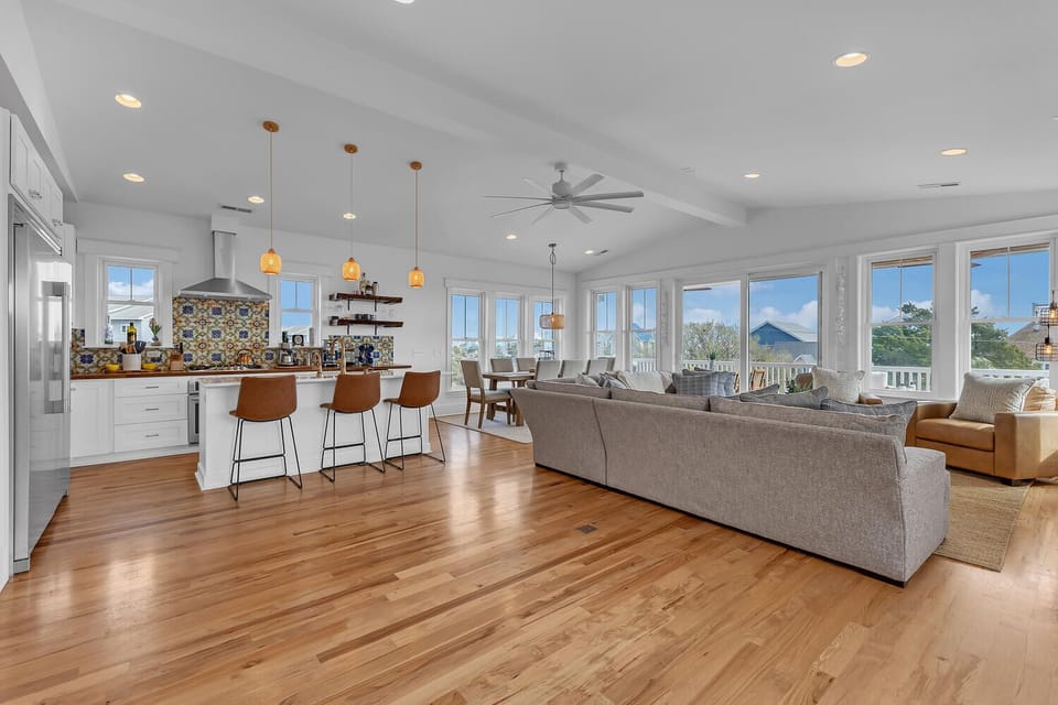 Relax in this stunning open-concept space where gleaming hardwood flows beneath soaring ceilings, connecting your gourmet kitchen to panoramic water views.