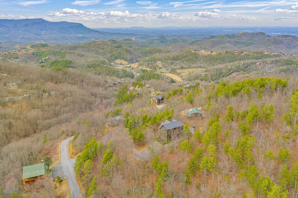 Aerial view showcasing the property nestled among rolling hills and mountain ridges in a scenic forested landscape.