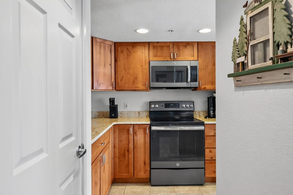Your fully equipped kitchen awaits with warm wood cabinets, granite counters, and modern appliances ready for your culinary adventures.