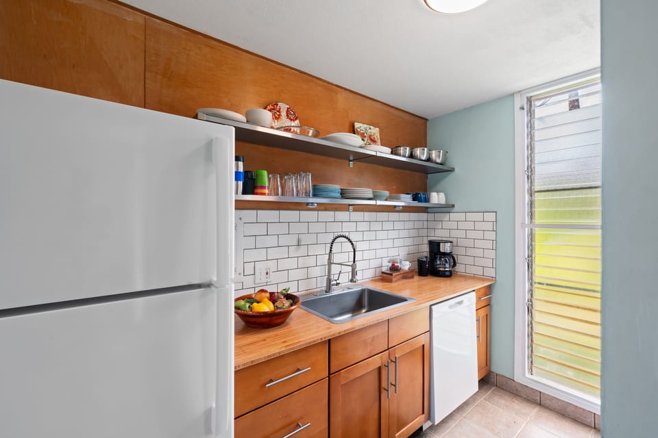 Well‑equipped kitchen featuring open shelving, tiled backsplash, and plenty of counter space for meal prep.