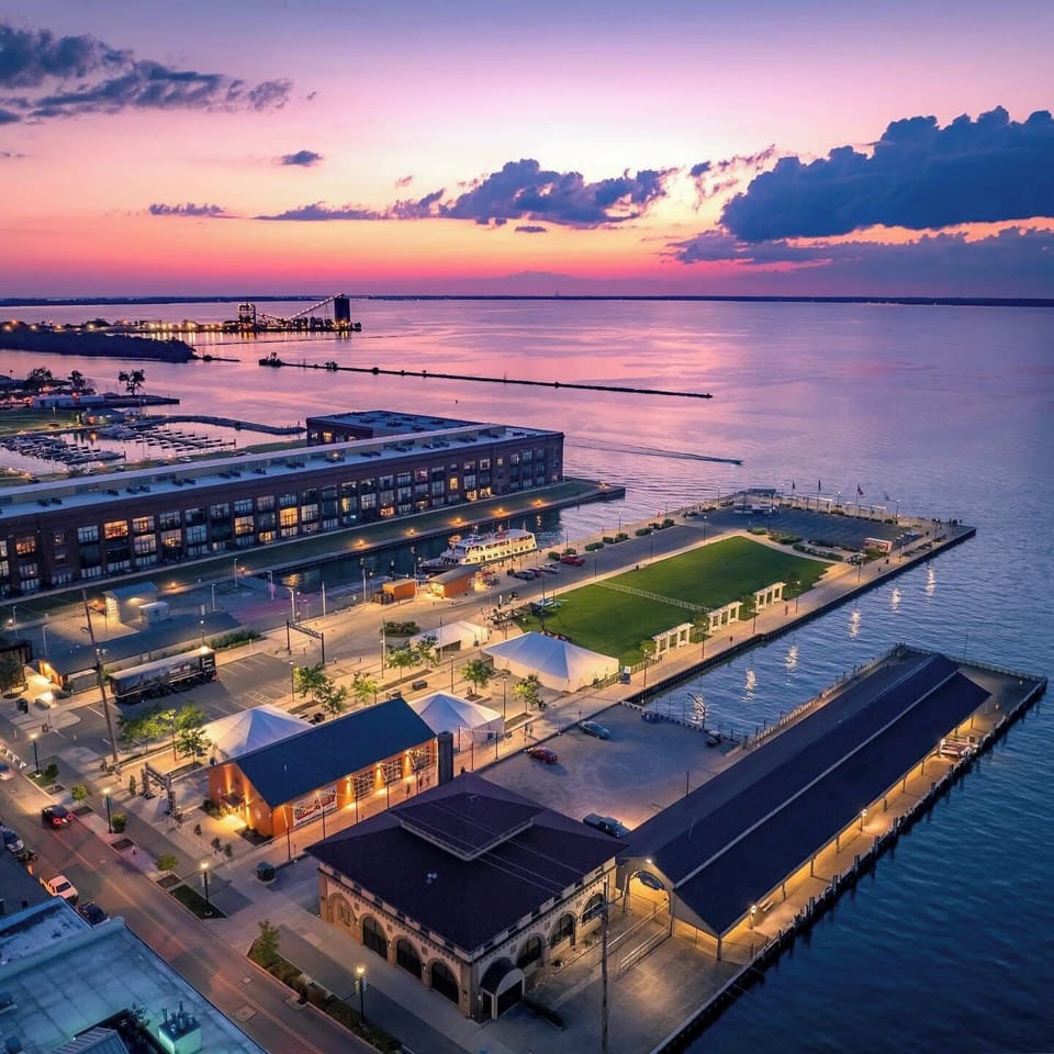 Waterfront property captured at sunset with vibrant pink and purple skies reflecting over calm waters.