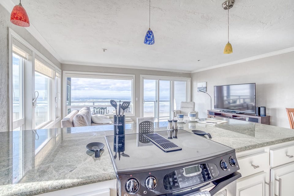 Your beachfront kitchen opens to stunning ocean views while you cook, with colorful pendant lights adding charm to this bright, modern space.