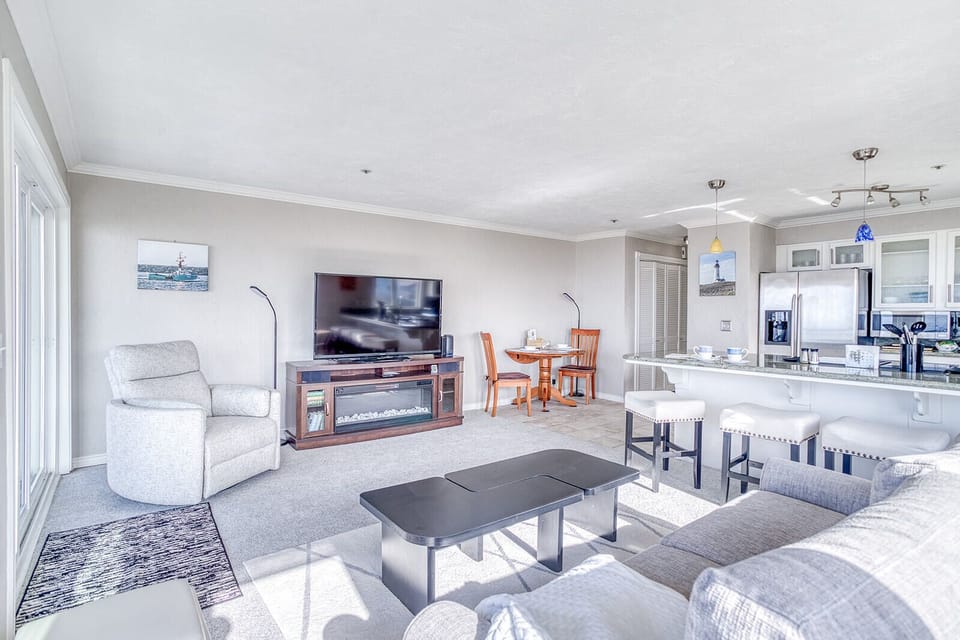 Relax in your bright, open-concept living space where modern comfort meets coastal charm with a cozy fireplace and spacious kitchen.