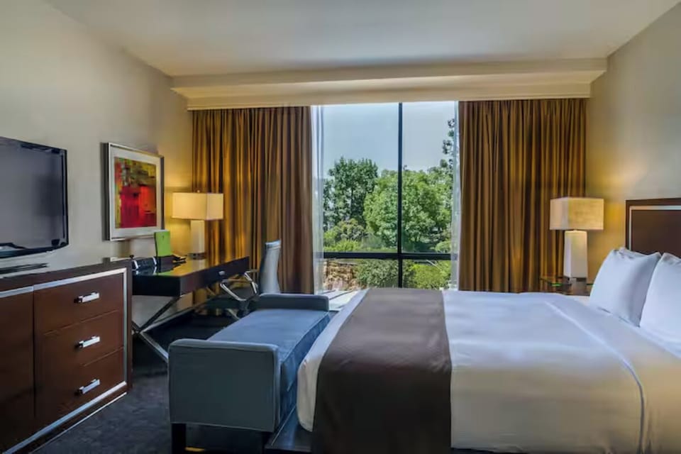 Unwind in crisp linens beside a sunlit picture window.