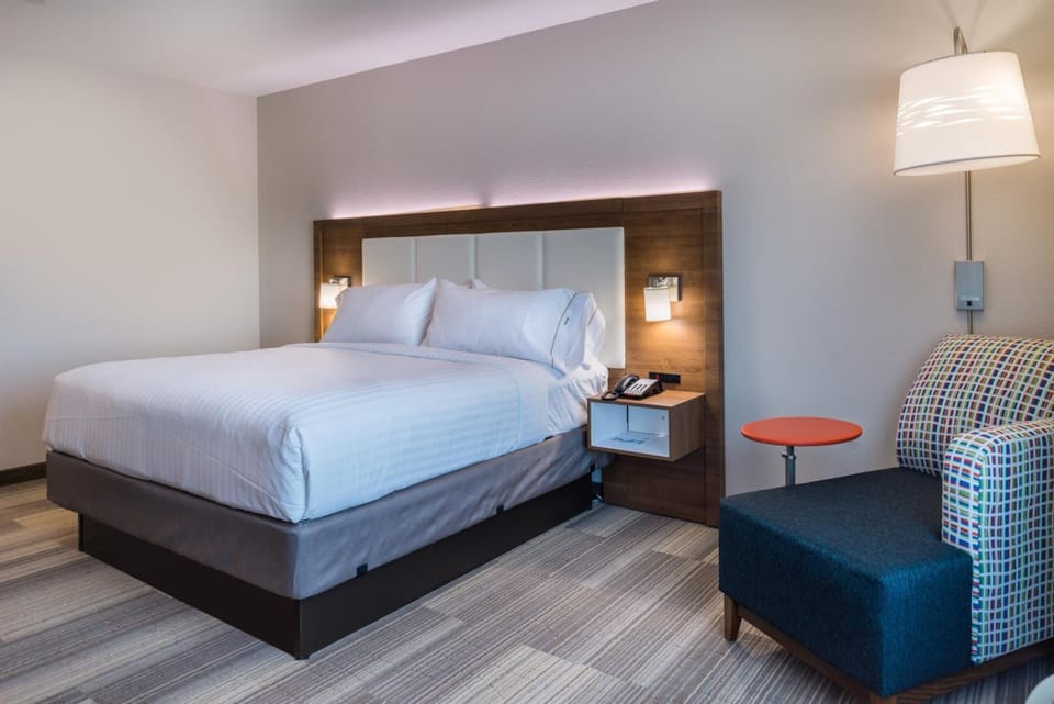 Unwind in crisp linens beneath warm, modern bedside lighting.