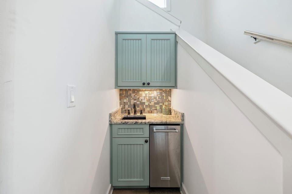 Your compact wet bar tucked under the stairs features sage cabinets, granite counters, and a mini dishwasher for easy entertaining.