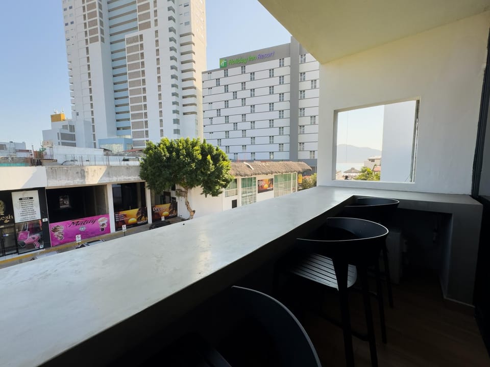 Cityscape views from a sleek, modern balcony bar seating area