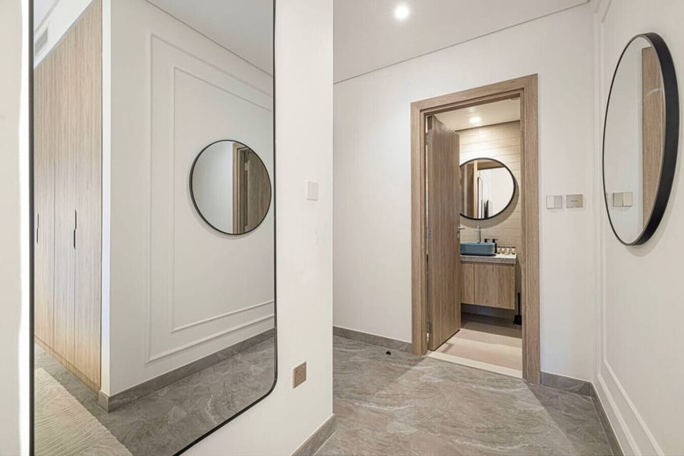 Sleek, mirror-lined corridor leading to a cozy bathroom.
