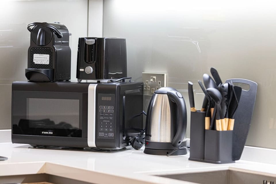 Modern countertop with coffee machine, toaster, kettle & full cooking utensils—everything you need to feel at home.
