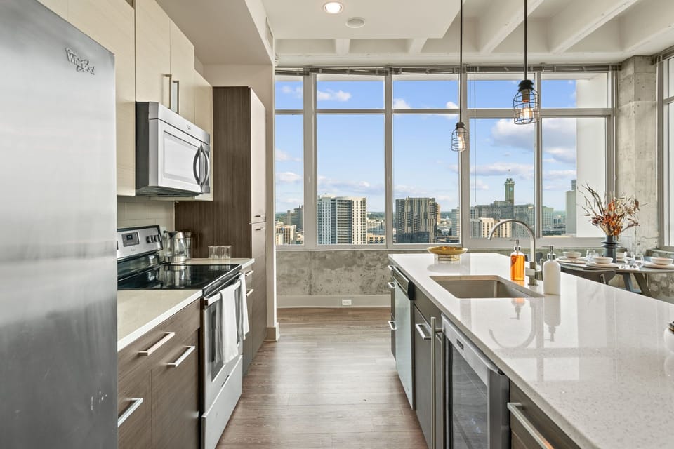 Cook with skyline views in a fully equipped kitchen featuring modern appliances and ample counter space. Perfect for morning coffee, quick bites, or hosting a relaxed dinner in Downtown Atlanta.
