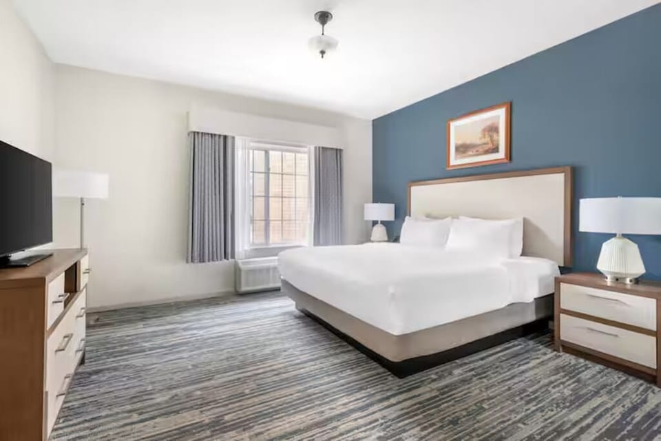 Stretch out comfortably in a spacious bedroom with calming tones.