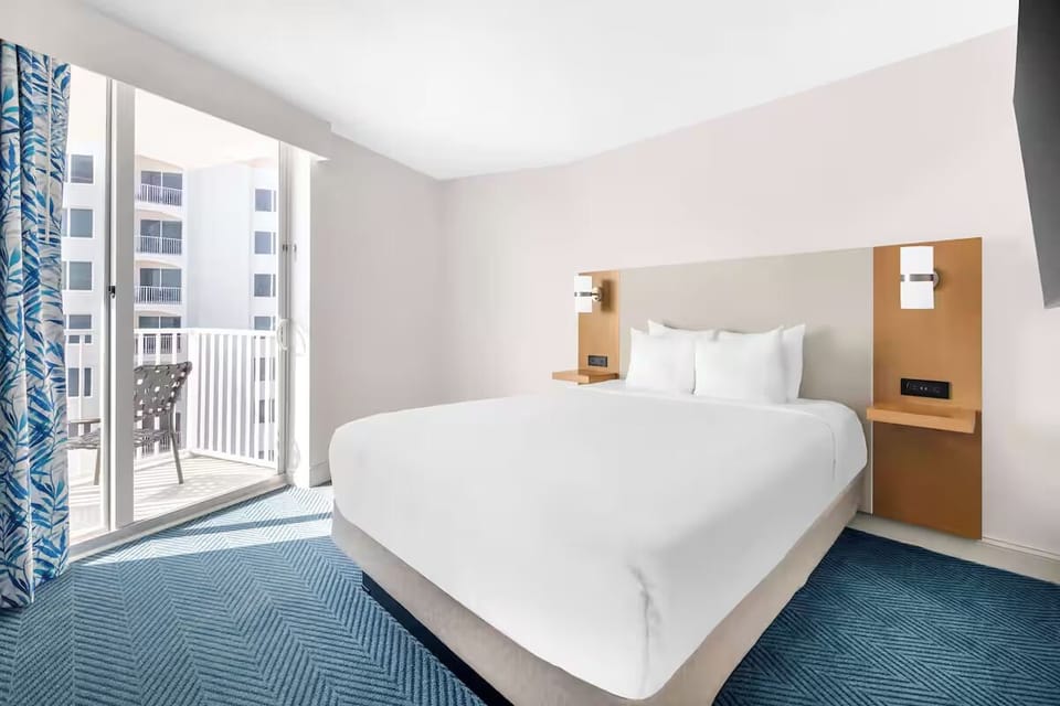 Unwind in a sunlit king bed steps from balcony breezes.