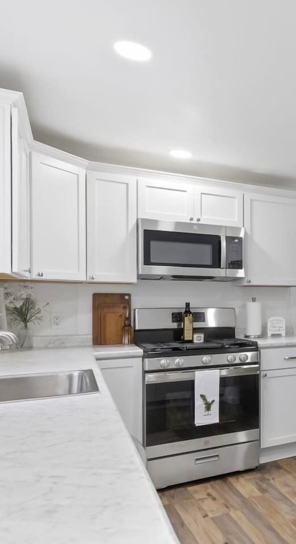 Fully equipped kitchen with white cabinetry, stainless steel appliances, and spacious marble-look countertops.