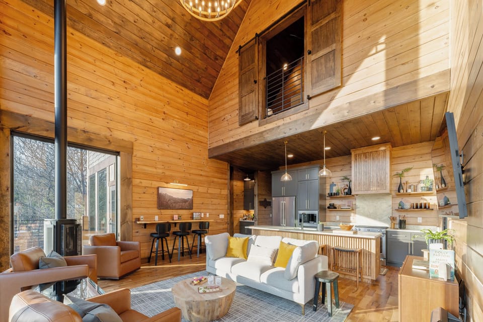 Open-concept living space with soaring ceilings, a cozy fireplace, and a fully equipped kitchen—perfect for gathering and making memories together.