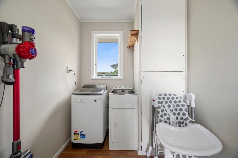 Dedicatedlaundry room with washing machine, clothes dryer, and wall-mounted Dyson vacuum — fully self-contained Rotorua holiday home