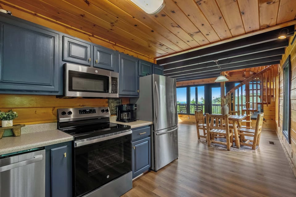 Slate-blue cabinets, stainless steel, and a window that lets you watch the mountains while the coffee brews — because cooking on vacation should feel this good.