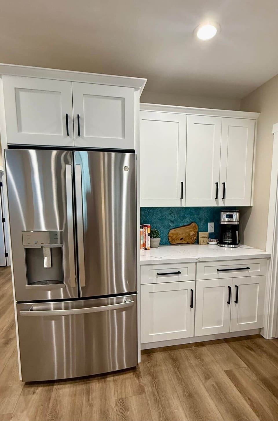 Stainless steel appliances and coffee nook near walk in pantry.