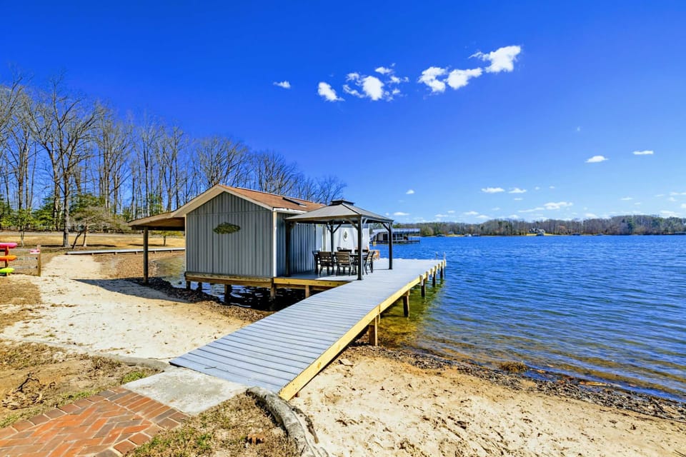Sandy Beach and Dock - A sandy shoreline leads to the private dock and converted boathouse, with the lake stretching out beyond.