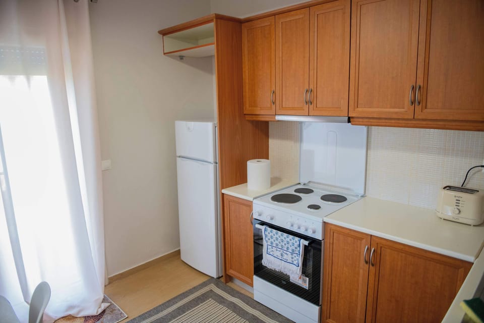 Bright, fully equipped kitchen with stove, oven, and ample cabinet space, filled with natural light from the window