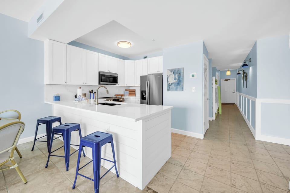 Your modern kitchen awaits with pristine white cabinets, stainless steel appliances, and a spacious island perfect for morning coffee or meal prep.