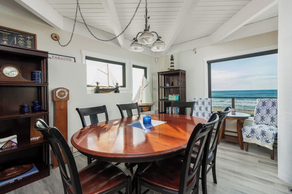 Gather around your nautical-themed dining table while waves crash just beyond the windows, creating unforgettable meals with stunning ocean views.