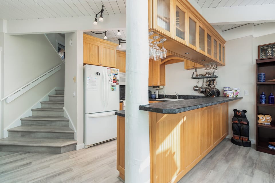 Your open kitchen features warm wood cabinetry, stone counters, and a breakfast bar perfect for morning coffee or casual meals together.