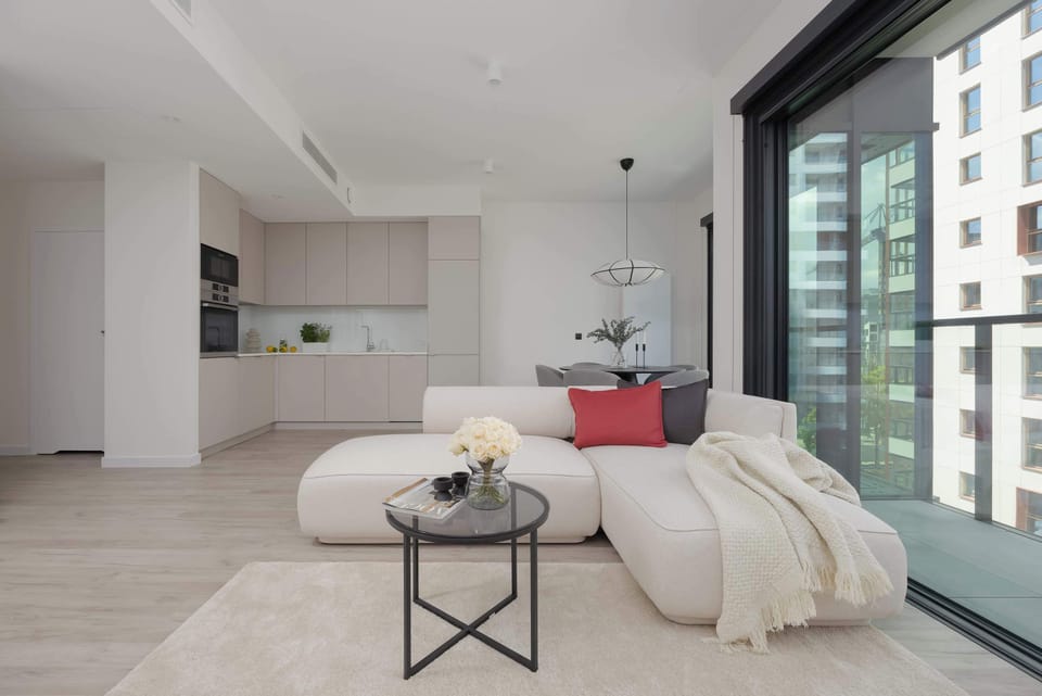 A bright and cozy living room with a comfortable sofa and elegant decor. Large windows let in plenty of daylight.