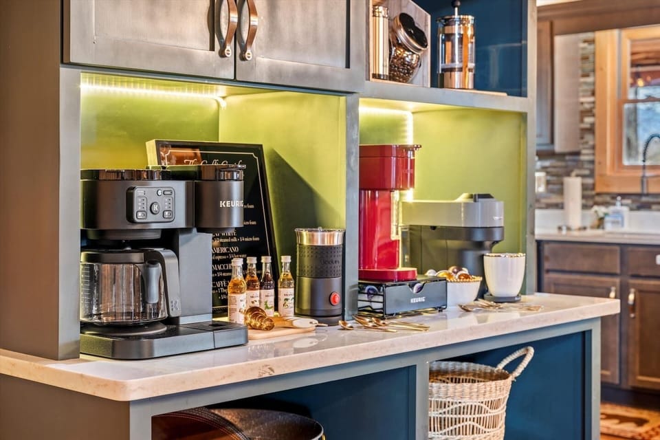 Your morning starts here — coffee maker, cups, and neon light already set up so the mountain routine begins without thinking.