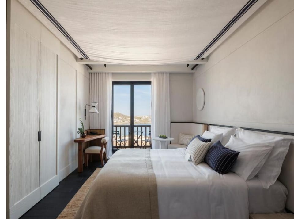 Unwind in crisp linens with balcony views beyond.