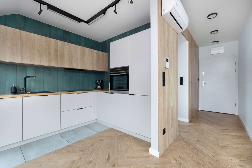 A kitchenette and hallway perspective demonstrates the seamless flow between the cooking area and the rest of the apartment. Integrated lighting under the cabinets adds both style and utility.