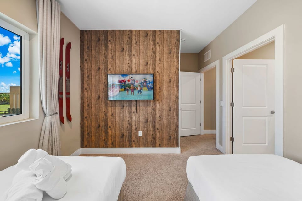 Cozy bedroom featuring a rustic wood accent wall and mounted flat-screen television.