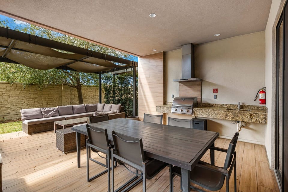 Covered outdoor dining area with a built-in grill and comfortable seating for gatherings.