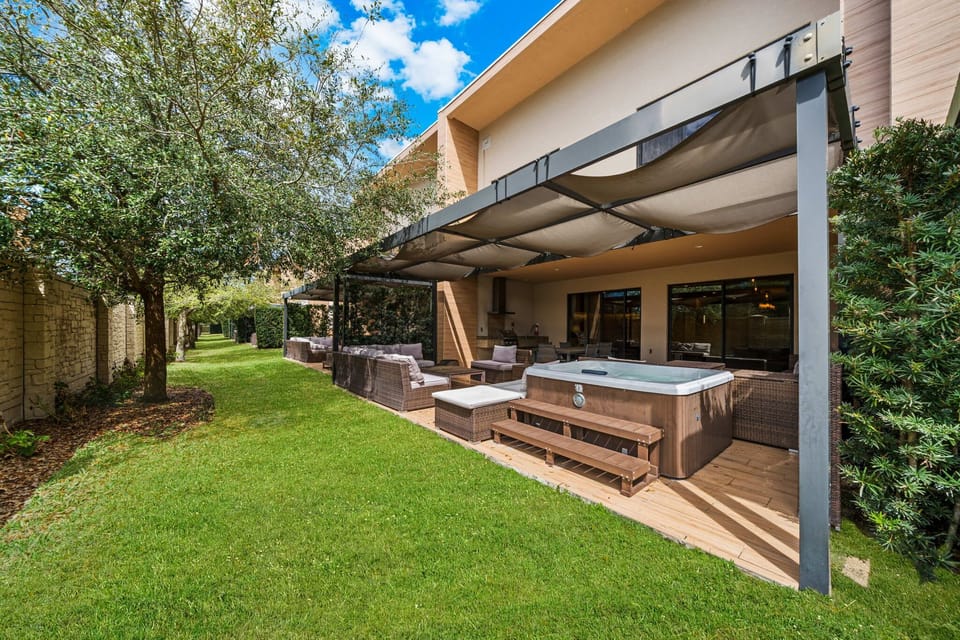 Relax in the shaded outdoor lounge area with a hot tub and garden views.